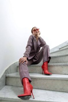 Woman in a patterned suit and red boots sitting on marble stairs