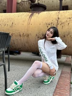 Woman in a white long-sleeve shirt and white thigh-highs squatting outdoors