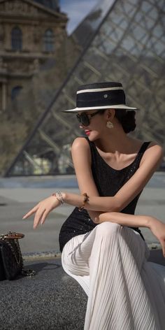 Woman in a boater hat and sunglasses with a sequin top and pleated skirt outdoors