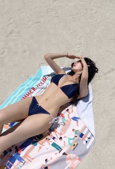 Woman in a dark blue bikini sunbathing on a beach towel