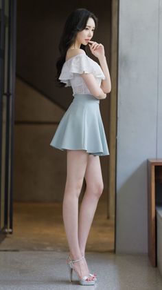 Woman in an off-shoulder top and mini skirt posing indoors