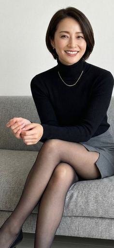 Woman with short hair wearing a black turtleneck and gray skirt, sitting on a sofa