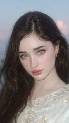 Woman with long dark hair and blue eyes wearing gold jewelry