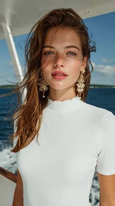 Woman with long hair and freckles wearing large earrings on a boat