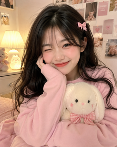 Young woman in a pink sweater winking and holding a stuffed bunny