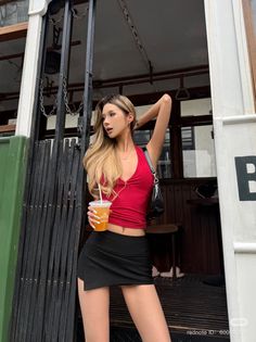 Woman in a red halter top and black mini skirt posing outdoors