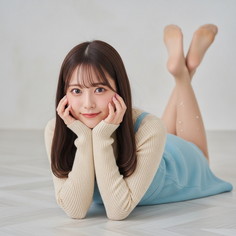 Woman with long hair wearing a light blue dress and beige sweater, lying on the floor