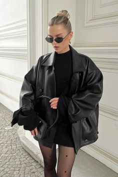 Woman in a black leather jacket and sunglasses with an updo hairstyle