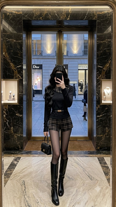 Woman in a black top and plaid shorts with black boots in a luxury store