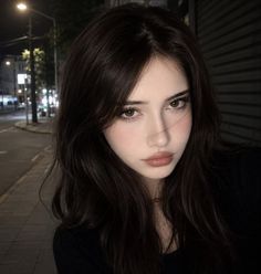 Woman with long dark hair on a street at night