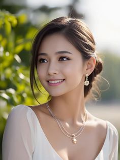 Smiling woman with an updo, wearing a white dress and jewelry outdoors