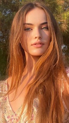 Woman with long hair and green eyes in a floral dress during golden hour