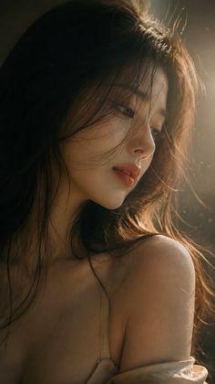 Woman with long hair and exposed shoulders in soft backlight