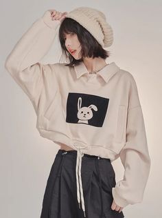 Woman with short hair and a beanie wearing a cropped sweatshirt with a bunny print