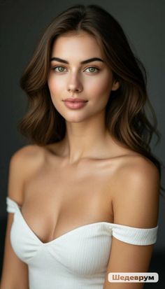 Woman with long brown hair and green eyes wearing a white off-shoulder top