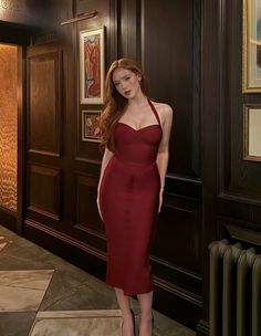Woman in a red halter dress standing in an indoor setting
