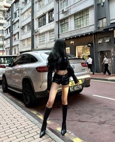 Person with long black hair in a leather outfit on a city street