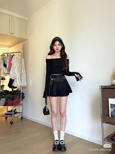 Woman in a black off-shoulder top and pleated skirt indoors