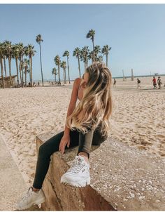 Woman with long blonde hair sitting on a concrete ledge at the beach