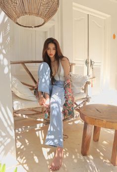 Woman with long hair wearing a white top and light wash jeans indoors