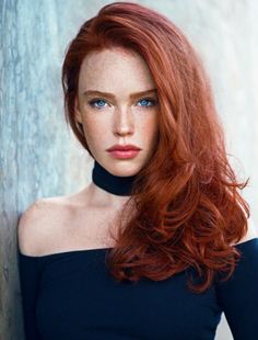 Woman with red hair and blue eyes wearing an off-shoulder top and choker