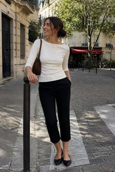 Woman in a white top and black pants standing on a cobblestone street