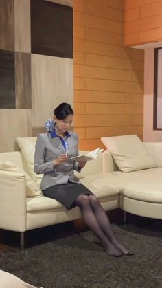 Woman in business attire sitting on a couch and reading a book