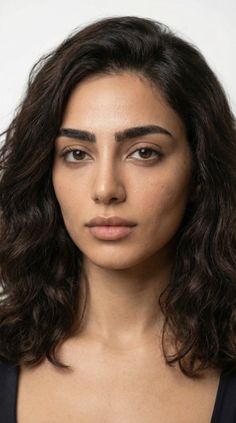 Close-up portrait of a woman with dark wavy hair and natural lighting