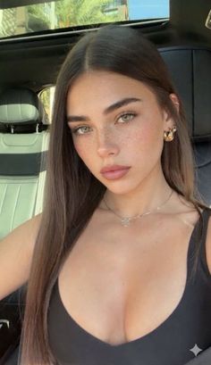 Woman with long hair and freckles in a black top inside a car