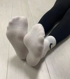Person wearing white socks and black leggings on a light wooden floor