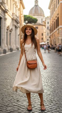 Woman in a straw hat and summer dress on a cobblestone street with a dome in the background