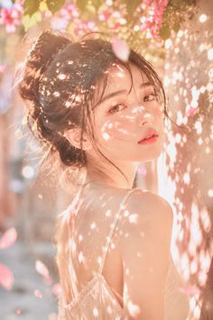 Woman with an updo in soft golden hour light with pink petals