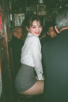 Woman in a white shirt and mini skirt smiling in a crowded bar