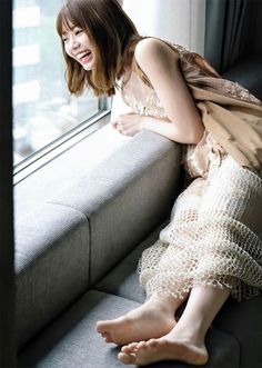 Woman with short hair and a lace dress sitting by a window, laughing