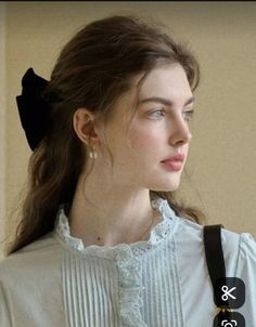 Woman with long hair and a black bow wearing a light blue ruffled shirt