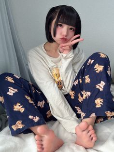 Woman with short black hair in teddy bear pajamas making a peace sign