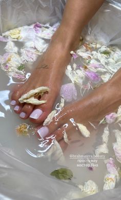 Feet soaking in water with flower petals, showing a fresh pedicure