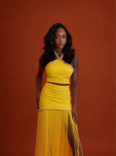Woman in a yellow halter top and fringe skirt with a high slit