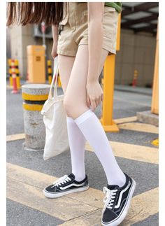 Person in khaki shorts and white knee socks standing on a street
