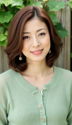 Woman with short brown hair and a green cardigan smiling outdoors