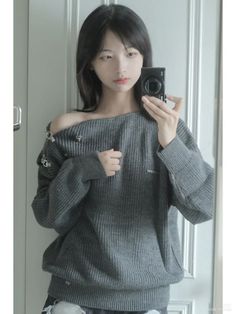 Woman in an off-shoulder sweater taking a mirror selfie