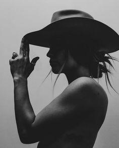 Woman in a cowboy hat with dramatic lighting and exposed skin