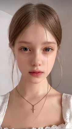 Young woman with long hair and a cross necklace looking directly at the viewer