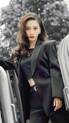 Woman with long wavy hair wearing a black blazer and crop top outdoors
