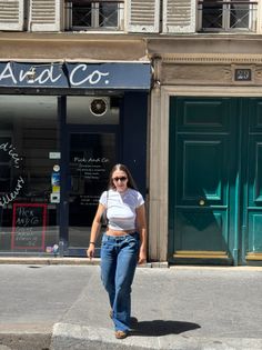 Woman in a white crop top and blue jeans walking on a sunny street