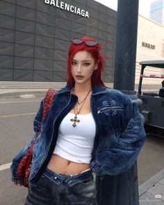 Woman with red hair in a denim jacket and crop top on a city street