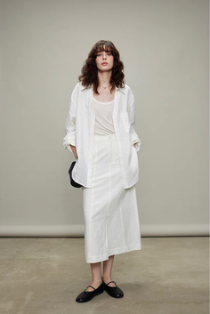 Woman in a white shirt and skirt with long wavy hair in a studio