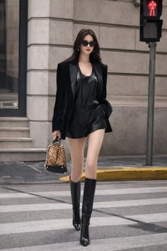 Woman in a black blazer and leather shorts crossing a street