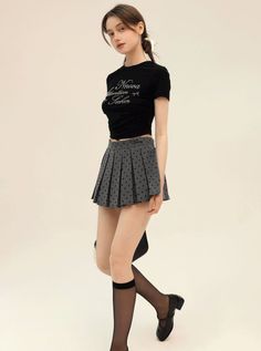 Woman in a black crop top and polka dot pleated skirt with knee-high socks
