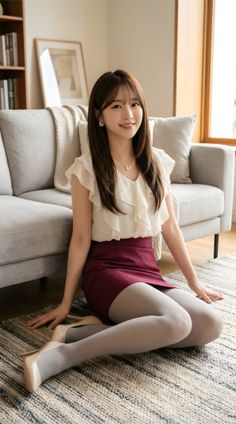 Woman in a ruffle blouse and mini skirt sitting on a rug indoors